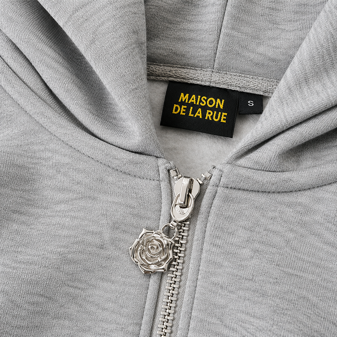 Signature Hoodie Product V4 Grey Melange. Graues Hoodie-Stoffdetail mit gesticktem Logo.