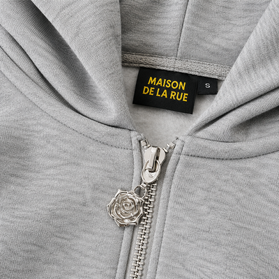 Signature Hoodie Product V4 Grey Melange. Graues Hoodie-Stoffdetail mit gesticktem Logo.