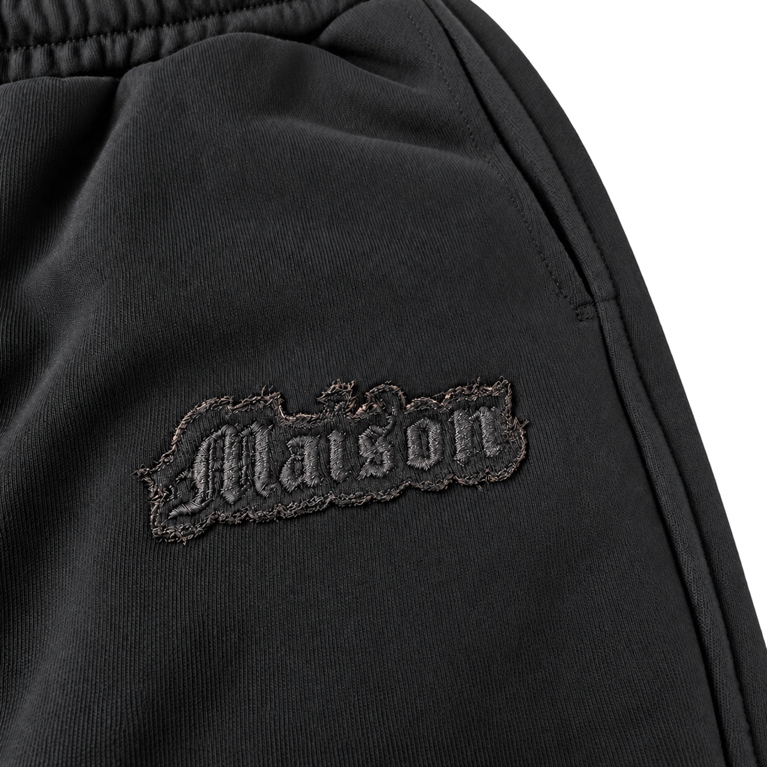Signature Sweatpants Product V3 Black. Nahaufnahme des gestickten Logos auf den schwarzen Maison De La Rue Sweatpants.