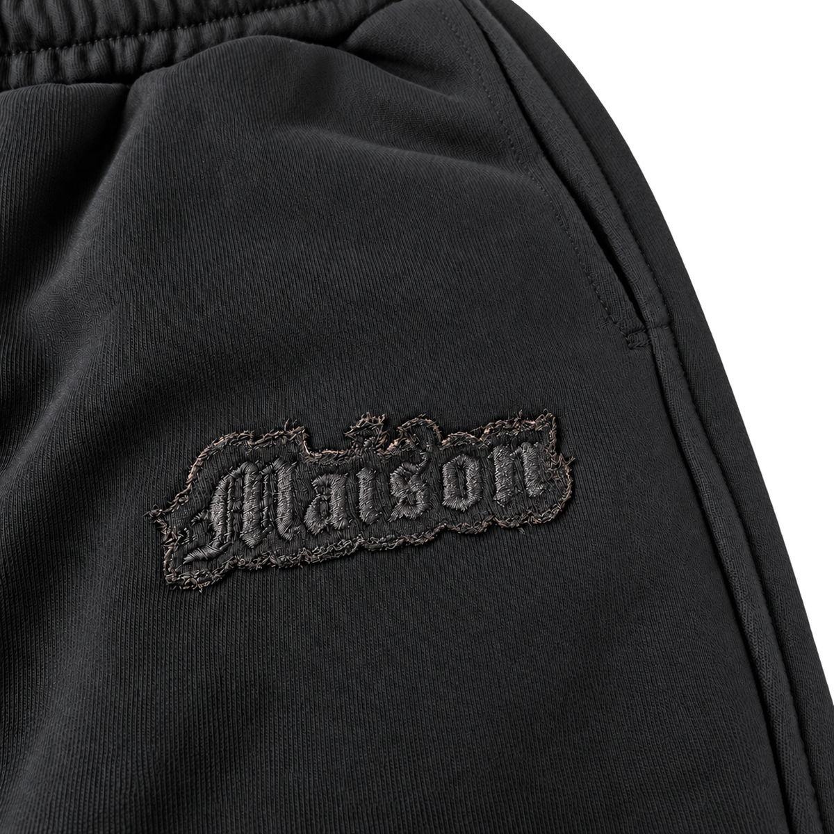Signature Sweatpants Product V3 Black. Nahaufnahme des gestickten Logos auf den schwarzen Maison De La Rue Sweatpants.